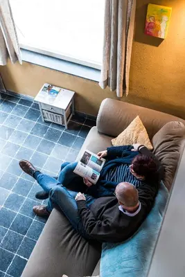 a woman laying on a couch reading a book at B&B Art.14 in Morkhoven