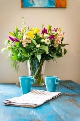 a vase of flowers sitting on a table with two cups at B&B Art.14 in Morkhoven