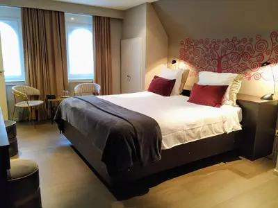 a hotel room with a large bed with red pillows at Hotel Lepelbed in Ghent