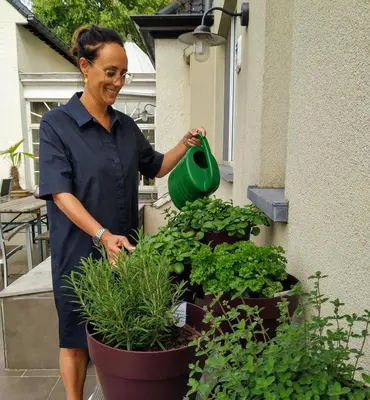 a woman watering plants in pots on a patio at Hotel Lepelbed in Ghent