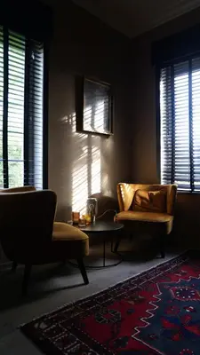 a living room with two chairs and a table and windows at Hotel Lepelbed in Ghent