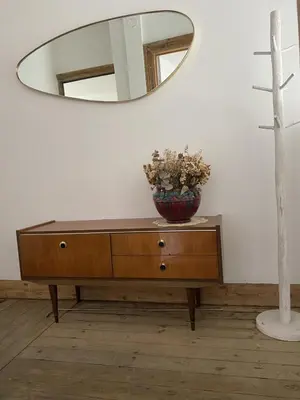 a dresser with a mirror and a vase with flowers on it at Rétro Studio in Brussels