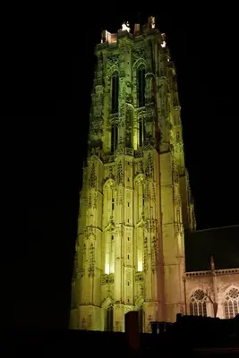 a tall clock tower at night with lights on it at Margaretha's Room in Mechelen