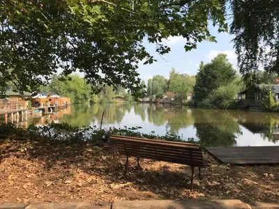 a park bench in front of a lake with a dock at Vakantiehuisje De Waterhoek in Geel