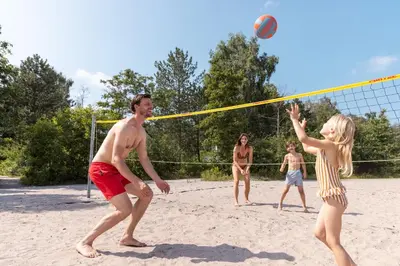 a group of people playing volleyball on a beach at Hotel Kempense Meren by Sunparks in Mol
