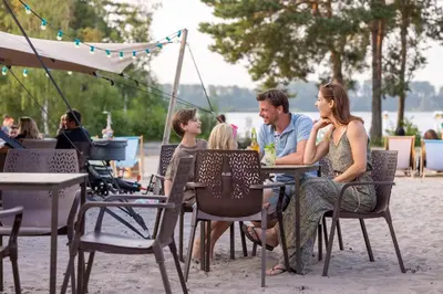 a group of people sitting at a table on the beach at Hotel Kempense Meren by Sunparks in Mol