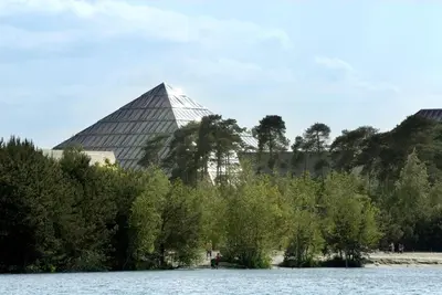 a view of a building and trees and water at Hotel Kempense Meren by Sunparks in Mol