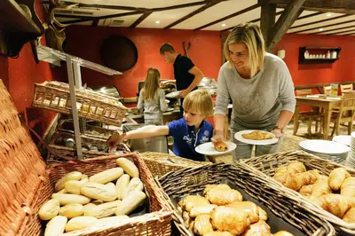 a woman and a child preparing food in a bakery at Hotel Kempense Meren by Sunparks in Mol