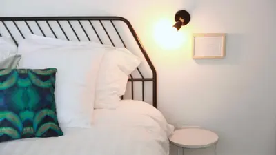 a bedroom with a bed with white pillows and a lamp at huisalfons in Mechelen