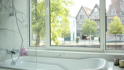 a bathroom with a bath tub and a window at huisalfons in Mechelen