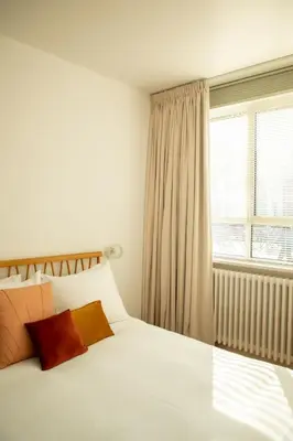 a bedroom with a white bed and a window at huisalfons in Mechelen