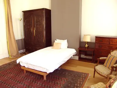 a bedroom with a bed and a dresser and a chair at Louise Chatelain suites in Brussels