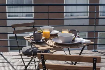 a table with cups and plates of food on a balcony at Studio Brussels Airport - North in Zaventem