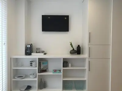 a white book shelf with a tv on a wall at Antwerp Town House Accommodations in Antwerp
