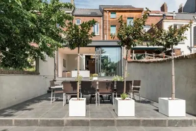 a patio with potted trees and a table and chairs at Flemishome, The Retreat For Family And Friends in Halle