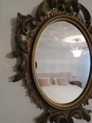 a mirror on a wall with a bed in a room at Guesthouse La maison de Fille in Diest