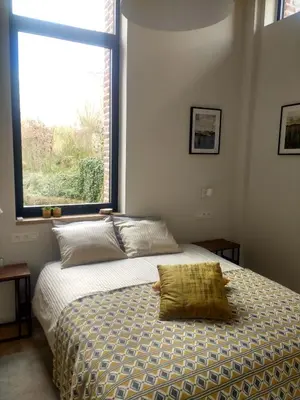 a bedroom with a bed with a large window at B&B De Woestijn in Roosdaal