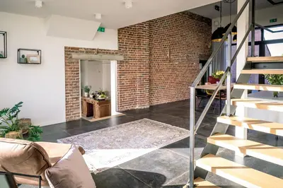 an open living room with a brick wall and stairs at B&B De Woestijn in Roosdaal