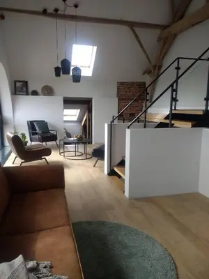 a living room with a staircase in a loft at B&B De Woestijn in Roosdaal