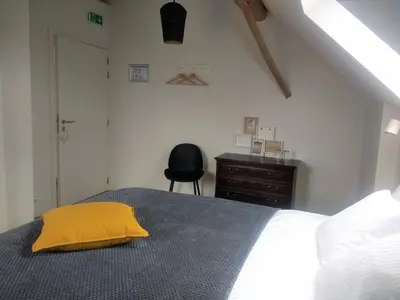 a bedroom with a bed with a yellow pillow on it at B&B De Woestijn in Roosdaal
