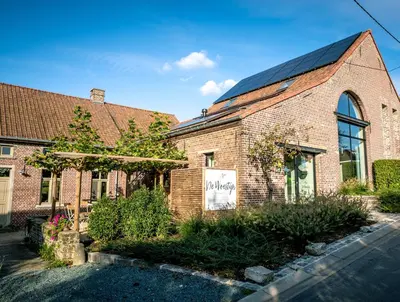 a brick building with a sign on the side of it at B&B De Woestijn in Roosdaal