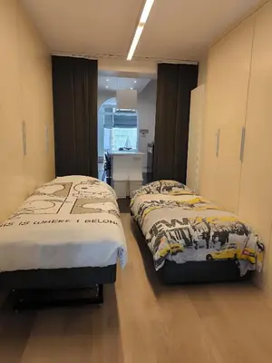 two twin beds in a room with a desk at Brugmann Loft Apartment in Brussels