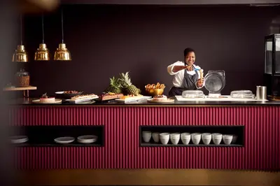a man standing behind a counter preparing food at Van der Valk Hotel Brussels Airport in Diegem