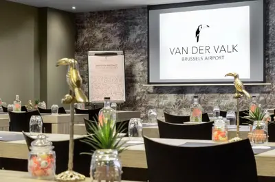 a meeting room with tables and chairs and a screen at Van der Valk Hotel Brussels Airport in Diegem
