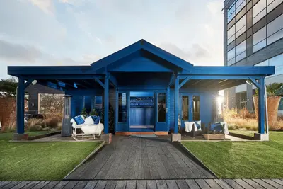a blue house with two white chairs on a deck at Van der Valk Hotel Brussels Airport in Diegem