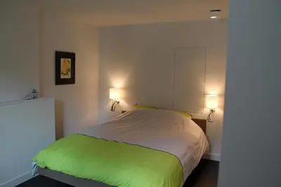 a bedroom with a green and white bed with two lights at Drabstraat 2 Apartment in Ghent