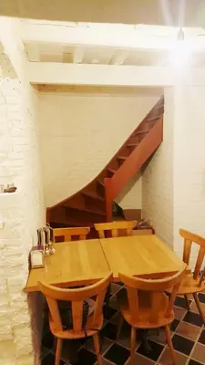 a wooden table with chairs and a staircase at Romantic 16th century workers house in Ghent