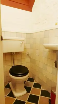 a bathroom with a toilet with a black lid at Romantic 16th century workers house in Ghent