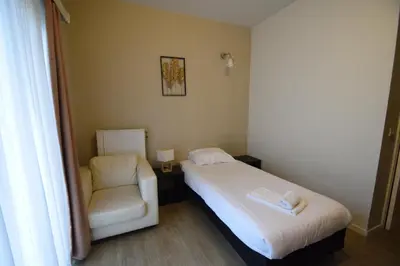 a small bedroom with a bed and a chair at Budget Flats Brussels in Brussels