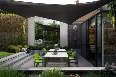 a patio with a white table and green chairs at Hotel Verlooy in Geel
