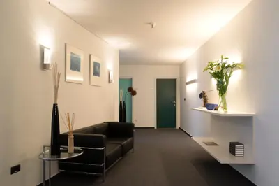 a living room with a black couch and a green door at Hotel Verlooy in Geel