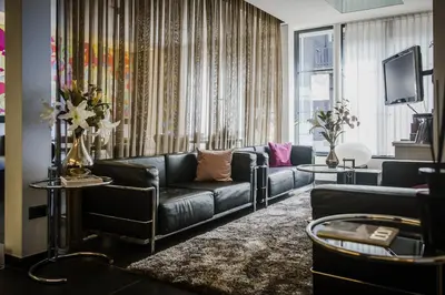 a living room with a black leather couch and a television at Hotel Verlooy in Geel