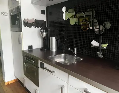 a kitchen with a sink and a black tile wall at La bellétage by Agelandkaai be with Free Parking in Ghent