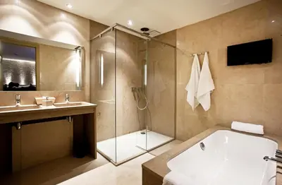 a bathroom with a shower and a tub and a sink at Hotel Thermen Dilbeek in Dilbeek