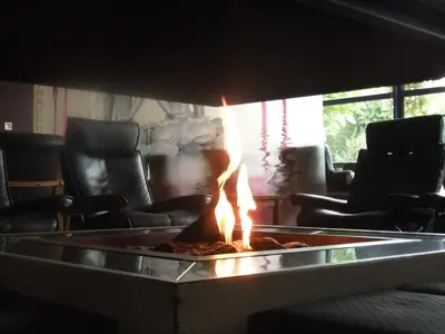 a fire pit in a living room with chairs at Hotel Thermen Dilbeek in Dilbeek