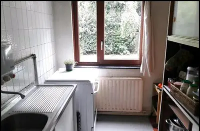 a small kitchen with a window and a sink at Chez Mimi - chambre vue parc in Brussels