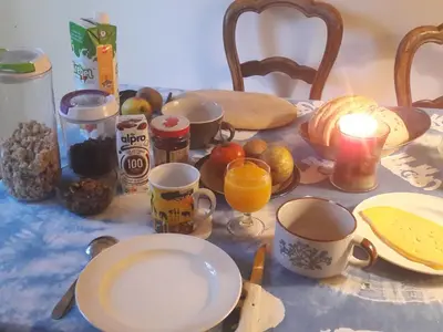 a table topped with cups and plates of food and fruit at Chez Mimi - chambre vue parc in Brussels