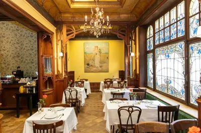 a dining room with tables and chairs and windows at Hotel Rubenshof in Antwerp