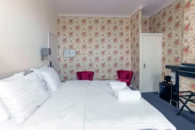 a bedroom with a white bed and two red chairs at Hotel Rubenshof in Antwerp
