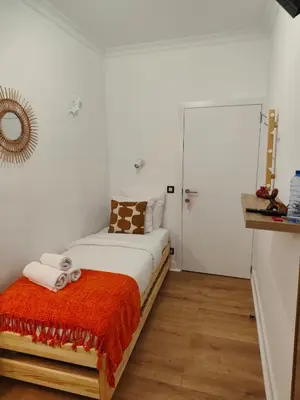a bedroom with a bed with a orange blanket at Hotel Rubenshof in Antwerp
