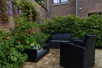 a patio with two wicker chairs and some bushes at Hotel De Pastorij in Leuven