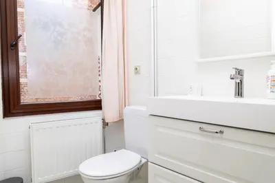 a white bathroom with a toilet and a sink at Hotel De Pastorij in Leuven