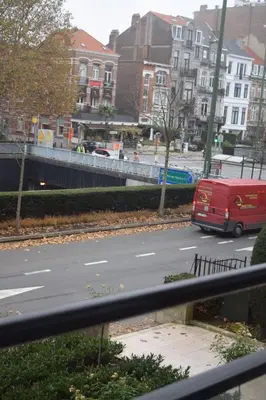 a red van is driving down a city street at Florya Studio Woluwe in Brussels