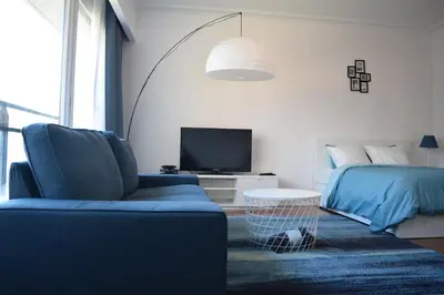 a bedroom with a bed and a blue couch and a tv at Florya Studio Woluwe in Brussels