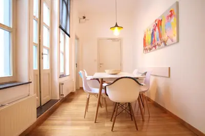 a dining room with a table and white chairs at Hoogpoort Residence George in Ghent