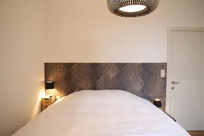 a bedroom with a white bed with a wooden headboard at Hoogpoort Residence George in Ghent